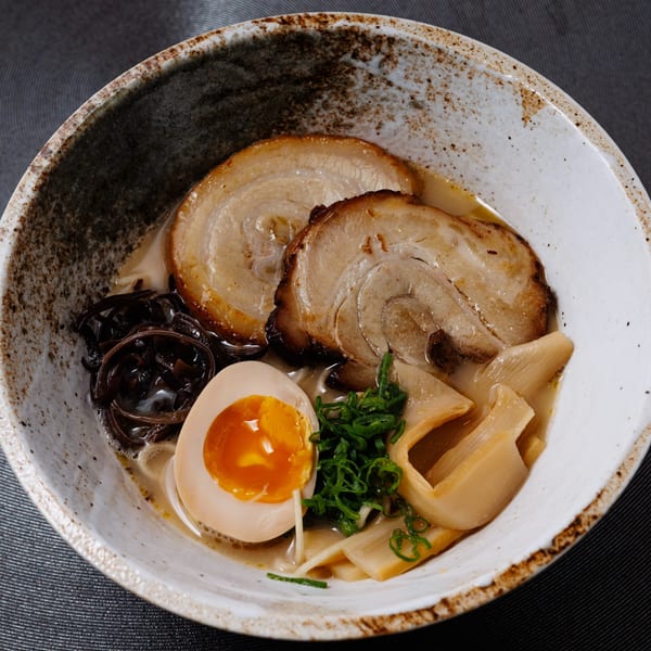 Kogane Ramen bowl with pork belly, soft-boiled egg, bamboo shoots, wood ear mushrooms, and scallions.